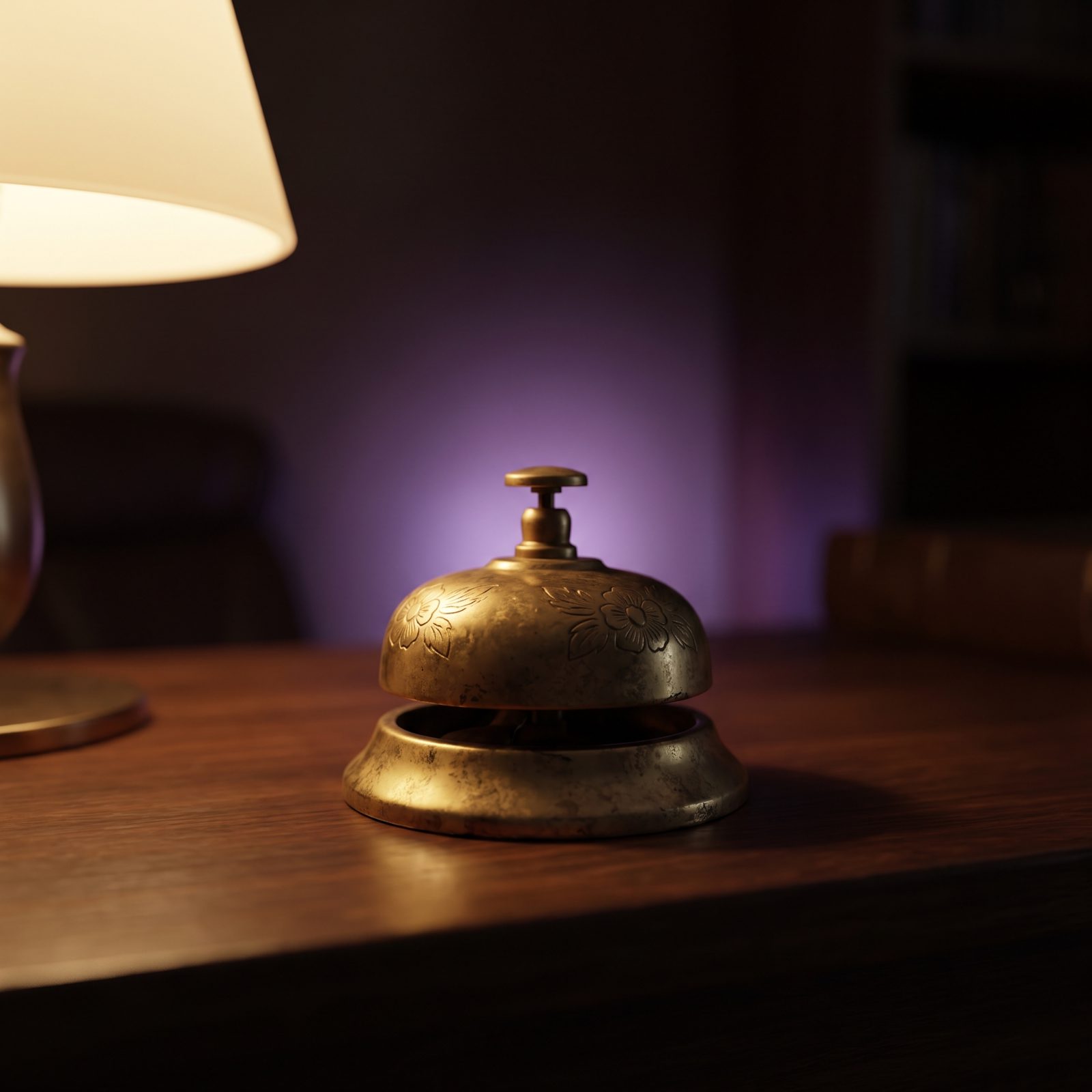 A brass desk bell on a dark walnut counter, lit warm with a violet glow behind